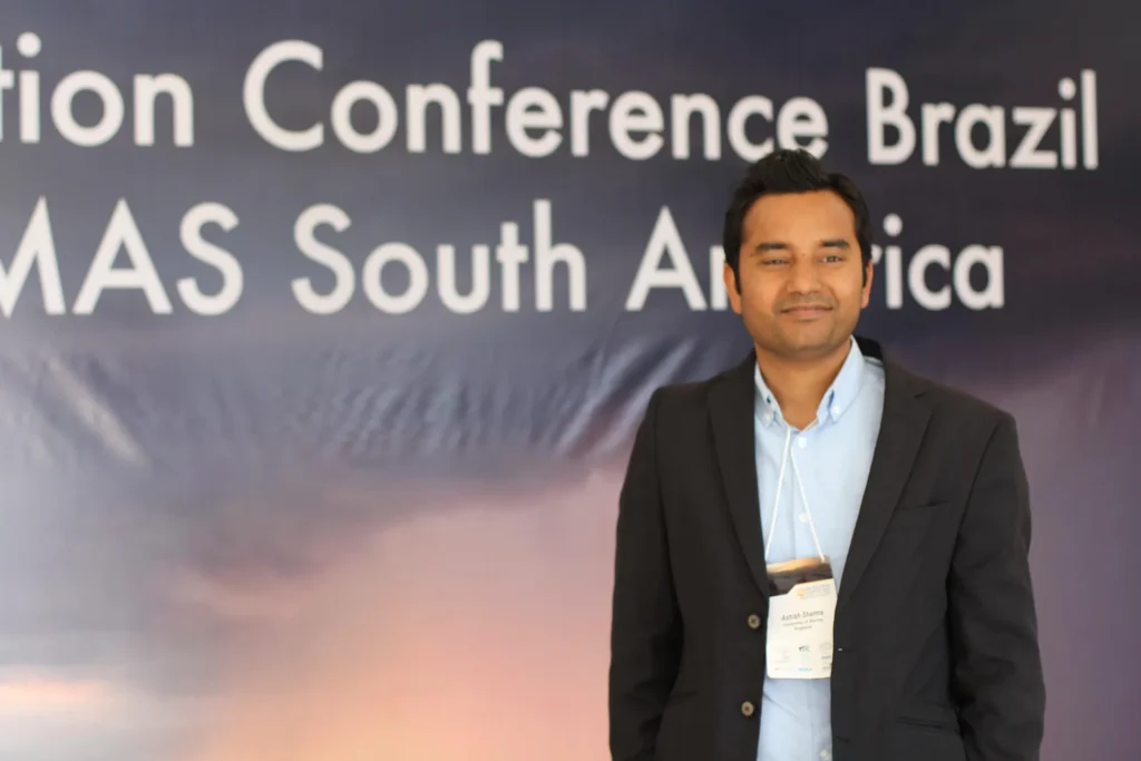 A participant beside the Air Pollution Conference Brazil backdrop.