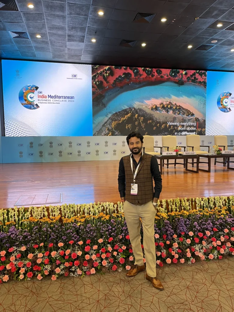 An attendee standing beside the India Mediterranean Business Conclave stage.