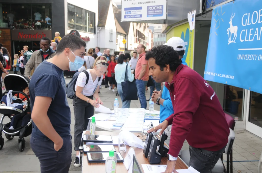 A researcher discussing leaflets and display materials with visitors.