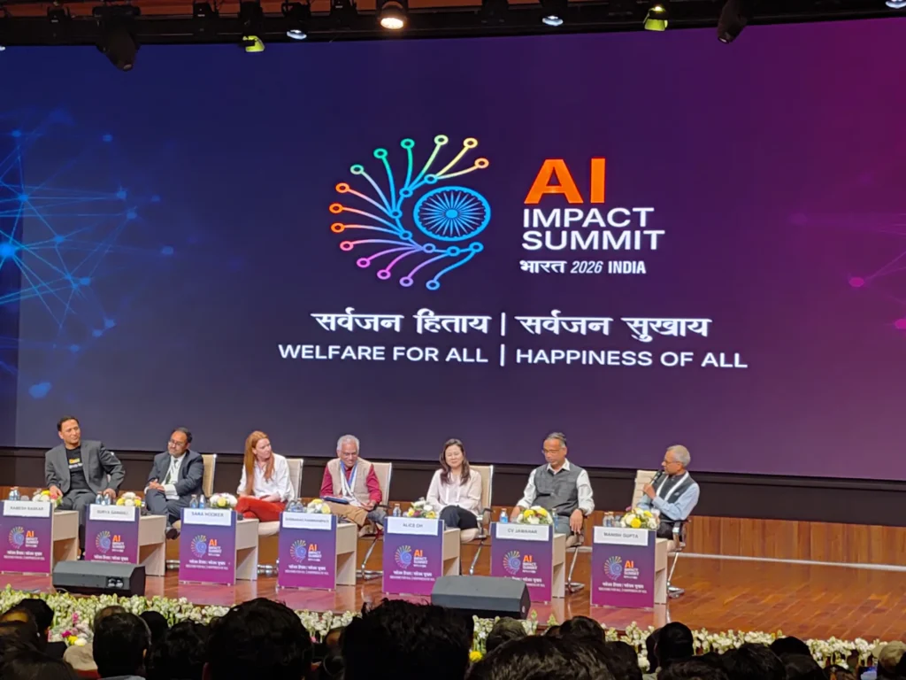 Panel members seated beneath the AI Impact Summit stage screen.