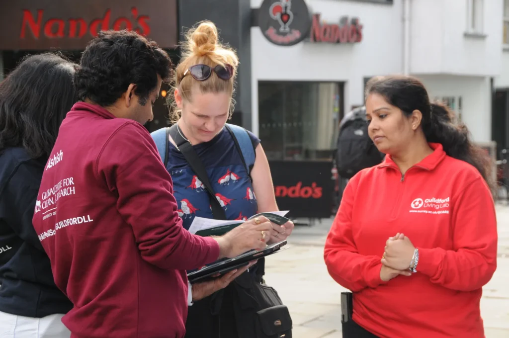 Visitors and researchers examining a handheld device at the outreach stand.